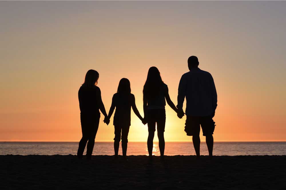 A family silhouette at the beach holding hands